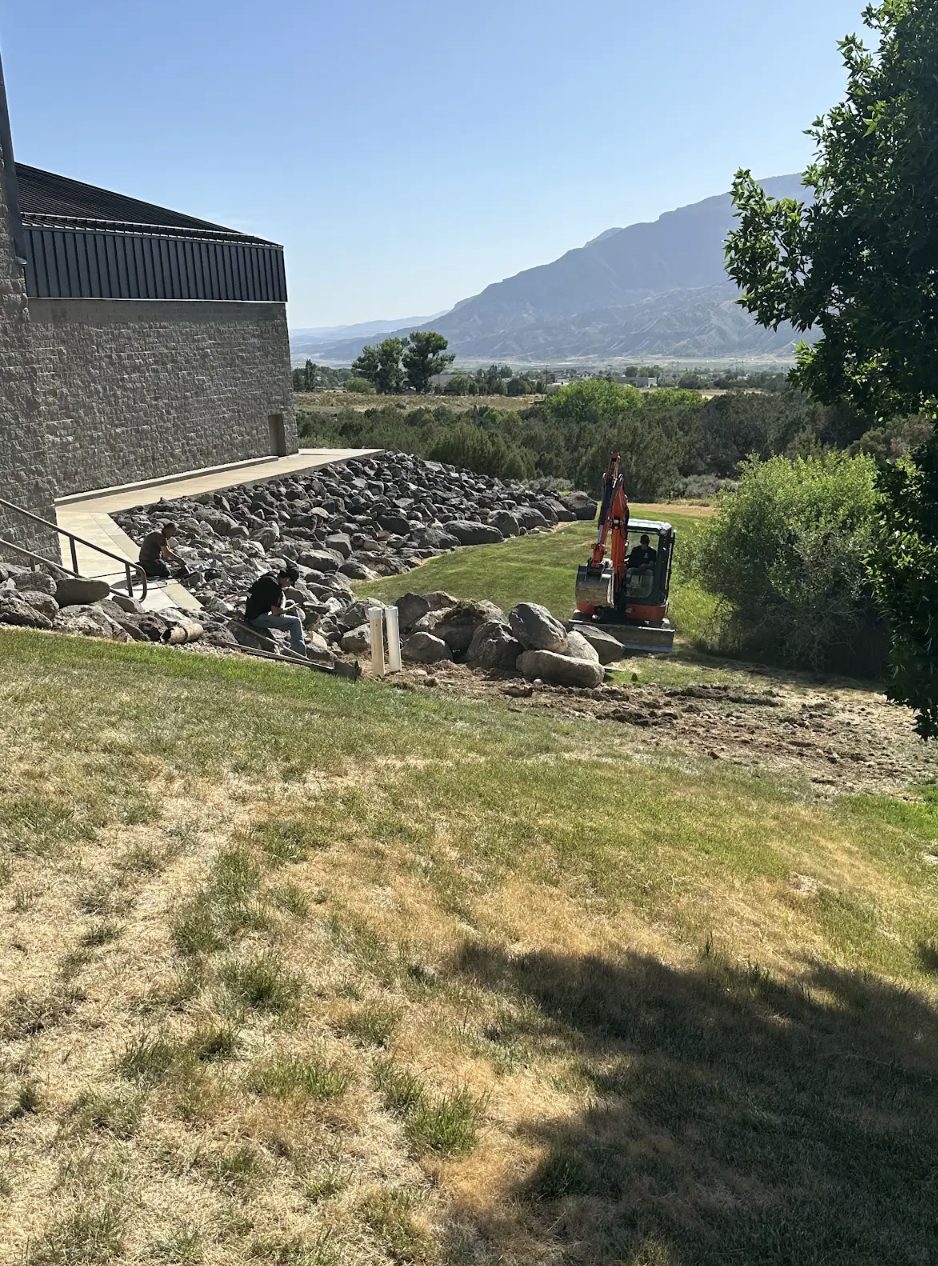 Elite Plumbing & Drains crew placing boulder retaining wall drainage