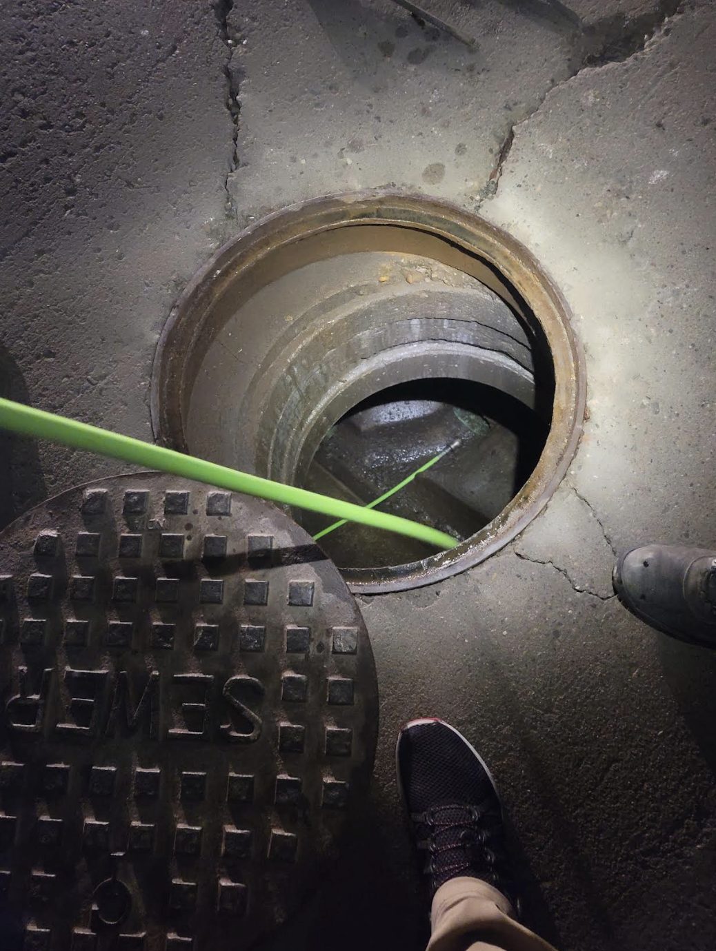 Sewer camera line lowered into a manhole