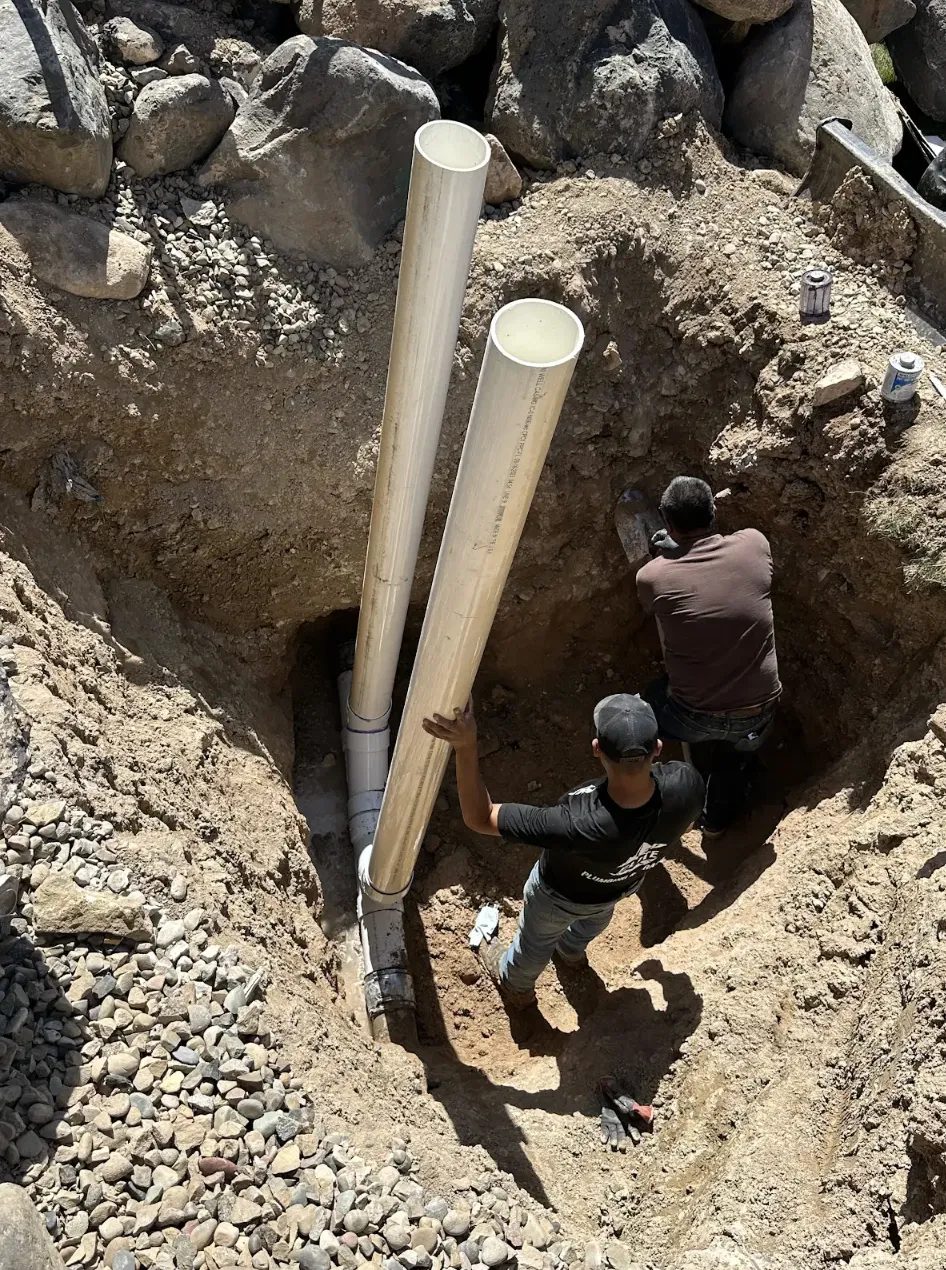 Elite Plumbing & Drains crew setting sewer pipe in a trench